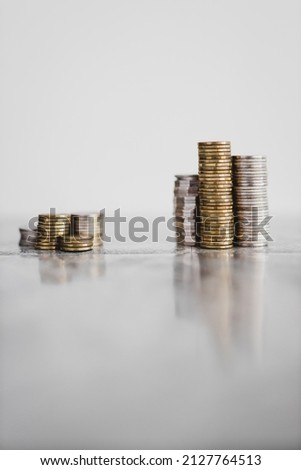 stacks of different coins divided between a small and a big group on white background, concept of good vs bad investements or before and after investing Royalty-Free Stock Photo #2127764513