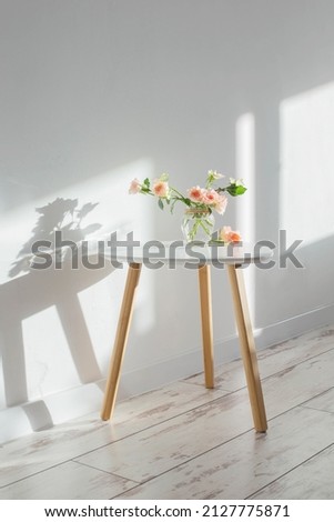pink roses in glass jar on white modern table on background white wall