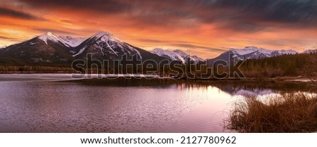 Panorama of Mountains illuminated by sunset in Banff National Park. The Vermillion Lakes are a destination for outdoor activities like paddling and seeing wildlife in the canadian rockies Royalty-Free Stock Photo #2127780962