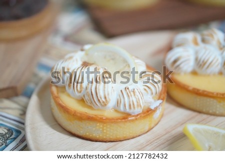Homemade lemon meringue tart on a wooden plate