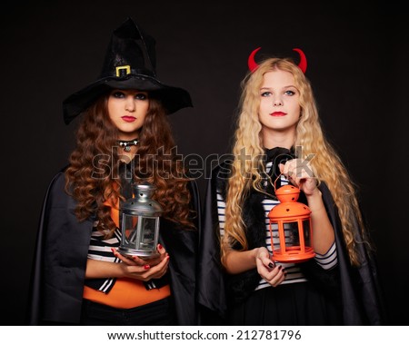 Halloween girls with lanterns looking at camera in the dark