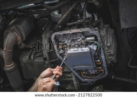 Auto mechanic installing a new automatic transmission filter. Royalty-Free Stock Photo #2127822500