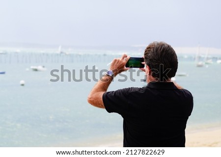 Back view of tourist young man taking picture in sea beach coast