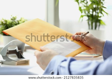 Man holding yellow envelope and going to fill in personal address on cover