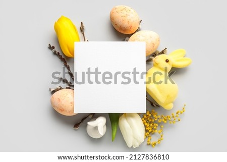 Beautiful Easter composition with blank card, eggs and flowers on white background