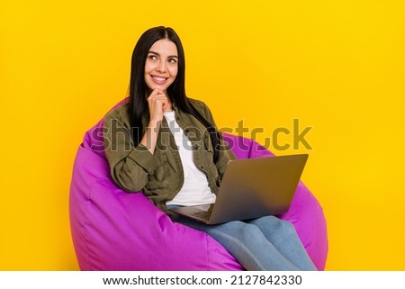 Photo of funny millennial lady look empty space hold laptop wear shirt jeans isolated on yellow background