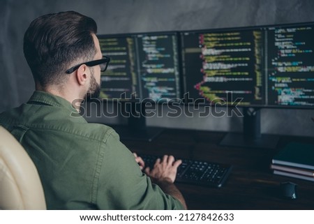 Photo of smart busy young man wear green shirt spectacles programming database writing code indoors workplace workstation