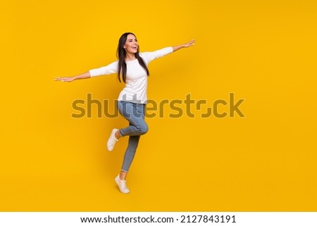 Full length photo of young adorable lady have fun hands wings airplane isolated over yellow color background