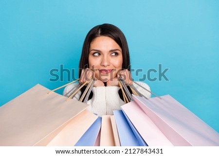 Photo of funny sweet woman wear white cardigan looking empty space holding bargains isolated blue color background