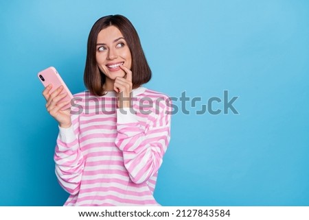 Photo of impressed millennial brunette lady hold telephone look promo wear striped pullover isolated on blue background