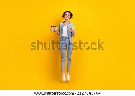 Full length photo of young girl jumper use smartphone download app 4g latte isolated over yellow color background