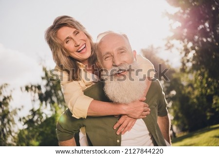 Photo of funny childish pensioner friends dressed casual shirts smiling holding hands arms piggyback walking outdoors urban city park