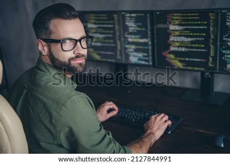 Photo of cheerful positive young guy dressed khaki shirt glasses creating new software indoors workshop workplace