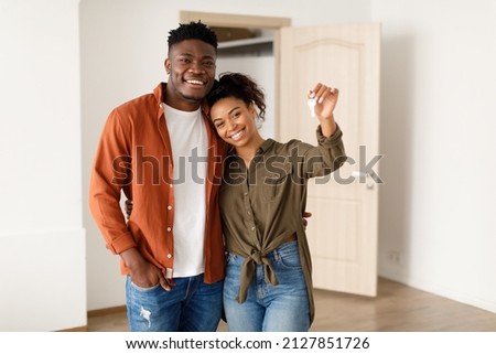 Real Estate. Cheerful African American Spouses Showing New House Key Smiling To Camera, Embracing Standing Among Moving Cardboard Boxes At Home. Relocation, Apartment Ownership And Family Housing Royalty-Free Stock Photo #2127851726
