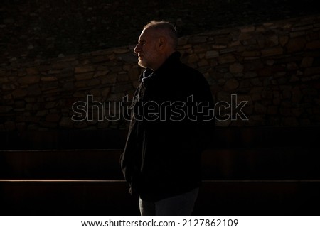 Portrait of adult man in winter cloth on street with sunlight and shadow