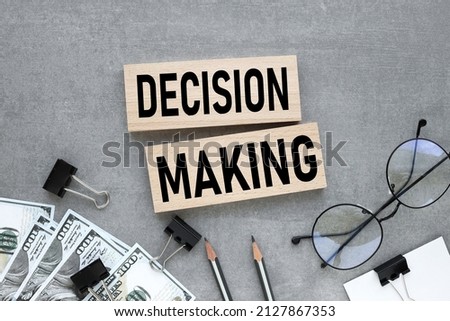 Decision making text on wooden blocks on a gray background near glasses and banknotes of money