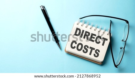 DIRECT COSTS text written on notepad on the blue background