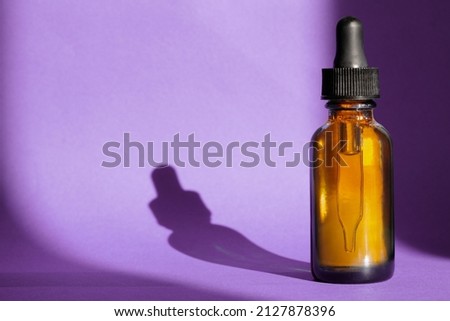 Mock-up of bottle with dropper on purple background. Herbal cosmetics, natural organic cosmetic products, designing essential oil packaging. Minimal concept with space for copying. Natural light Royalty-Free Stock Photo #2127878396