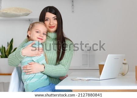 Happy little girl and her mother in warm sweaters sitting at home