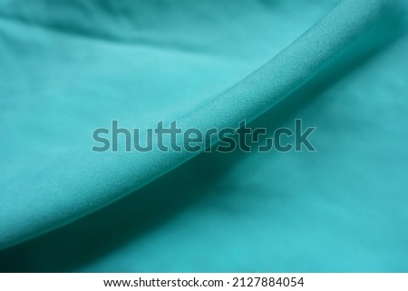 Diagonal fold on thin bluish green chiffon fabric