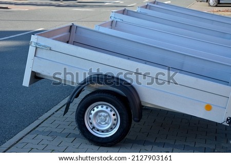 trailer behind a car in the parking lot at the rental shop. just harness to the ball of the towing device. homologation and technical inspections. metal side panels Royalty-Free Stock Photo #2127903161