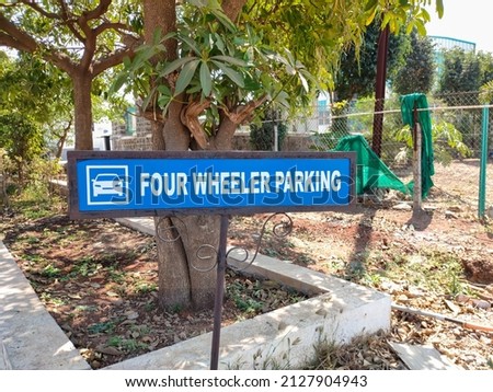 This is a sign board of four wheeler parking area. Here a lot of cars are parked.