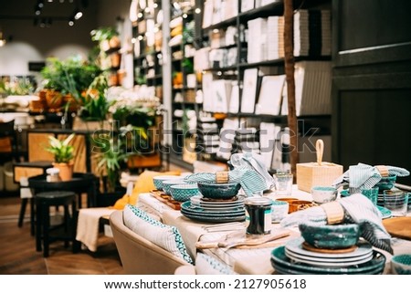 View of assortment of decor for interior shop in store of shopping center. Home accessories and household products for dining room in store of shopping centre. Home accessories of dinnerware on table Royalty-Free Stock Photo #2127905618