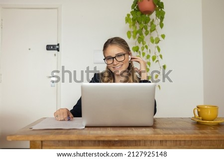 Young woman working at home with laptop and papers on desk and headphones.  Home office concept. Gray notebook for working. High quality photo