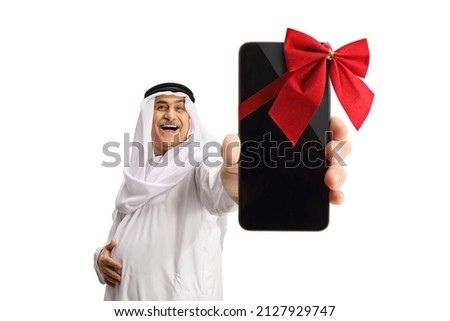 Mature arab man in dishdasha holding a smartphone with a red ribbon isolated on white background