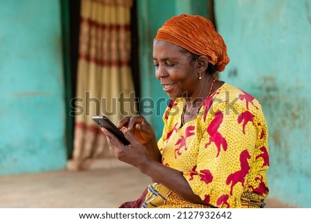 happy elderly african woman using her mobile phone Royalty-Free Stock Photo #2127932642