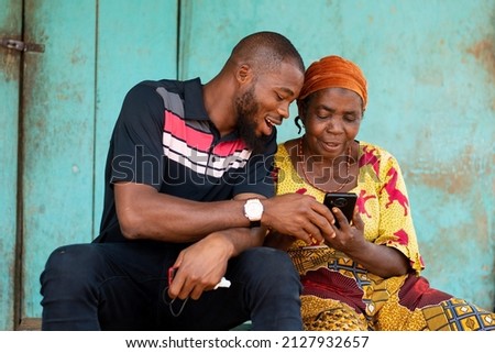young black man assisting an elderly woman using her phone Royalty-Free Stock Photo #2127932657
