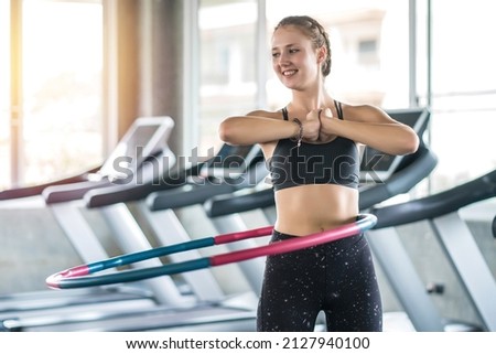 Young woman doing hula hoop during an exercise class in fitness gym. Healthy sports lifestyle, Fitness, Healthy concept. Royalty-Free Stock Photo #2127940100