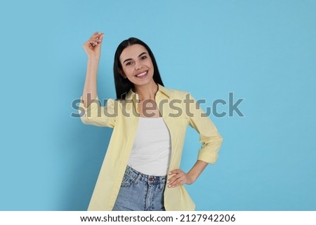 Young woman snapping fingers on light blue background. Space for text Royalty-Free Stock Photo #2127942206