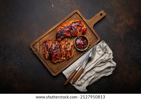 Grilled turkey or chicken marinated fillet with red sauce served and sliced on wooden cutting board on stone brown background from above, poultry breast barbecue  Royalty-Free Stock Photo #2127950813
