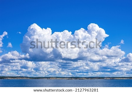 Skerries and coastline under a bright cloudy blue sky in the Koster fjord between the Koster islands and Strömstad, Bohuslän, Västra Götalands län, Sweden. Royalty-Free Stock Photo #2127963281