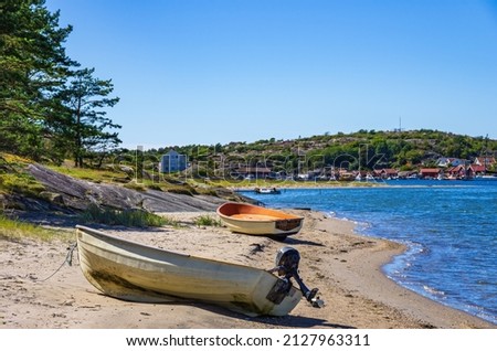 Two boats lie ashore on the North shore of Southkoster Island (Sydkoster) and beautiful view of the North Koster Island (Nordkoster), Bohuslän, Västra Götalands län, Sweden. Royalty-Free Stock Photo #2127963311