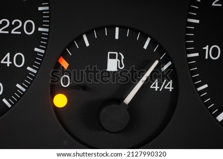Car fuel gauge scale with orange reserve light on. Close up macro shot, no people.
