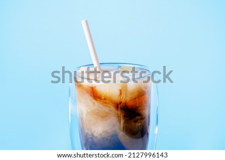 Coffee with milk and ice in a glass cup on a blue background. Royalty-Free Stock Photo #2127996143