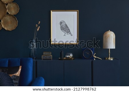 Creative composition of glamour living room interior design with mockup poster frame, wooden commode, lamp and elegant personal accessories. Dark blue wall. Home staging. Template. Copy space. Royalty-Free Stock Photo #2127998762