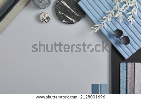 Flat lay composition of stylish architect moodboard with samples of textile, paint, blue wooden lamella panels and tiles. White, black, blue and light grey color palette. Copy space. Template.