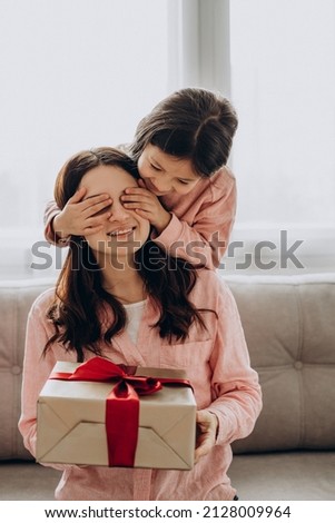 Little girl presenting gift box to her mother and closing her eyes