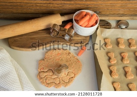 Making homemade healthy carrot dog treats. Dough with cookie cutters.   Royalty-Free Stock Photo #2128011728