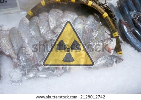 A basket of seafood and distant sea fish with a warning about nuclear radiation.contaminated foods.Radioactive soil.metaphor for nuclear threat.Nuclear leak,Environmental damage.white background. Royalty-Free Stock Photo #2128012742