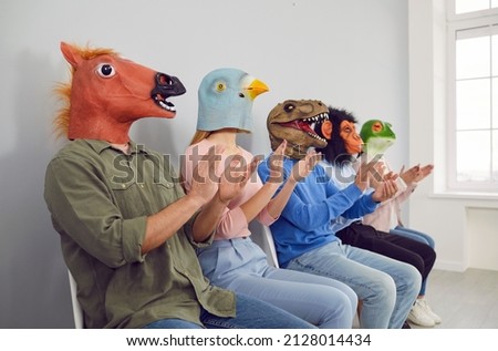 Audience in different funny bizarre silly animal masks applauding at interesting lecture or workshop. Group of happy foolish people with horse, bird, dino, ape and frog faces clapping hands at seminar Royalty-Free Stock Photo #2128014434