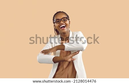 Overjoyed young African American woman isolated on pink studio background dancing and laughing. Happy millennial black girl in glasses have fun make dancer moves, celebrate success.