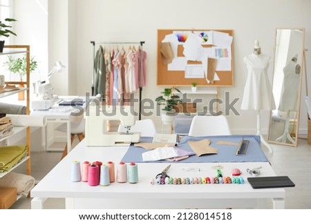 Empty fashion atelier of designer or seamstress with threads and sewing machine on table. No people in own stylish workshop of tailor or dressmaker. Clothing garment design. Style and dressmaking. Royalty-Free Stock Photo #2128014518