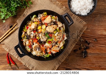 Chinese style cod, prepared in a wok. Natural wooden background. 