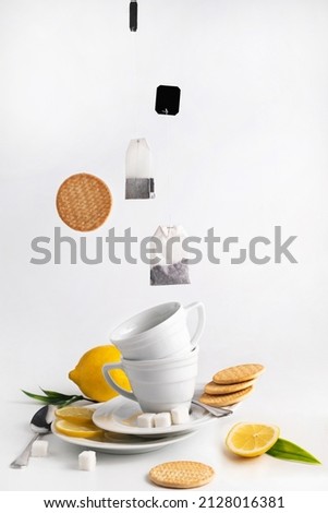 On a white background, two cups of tea, plates, cookies, lemon slices and levitation of tea bags and cookies.Tea party concept.