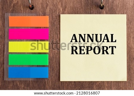 the text ANNUAL REPORT on a yellow card on a wooden background