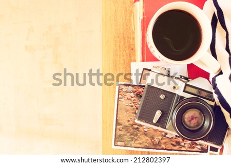 top view of old camera, cup of coffee and stack of photos. filtered image. travel or vacation concept.